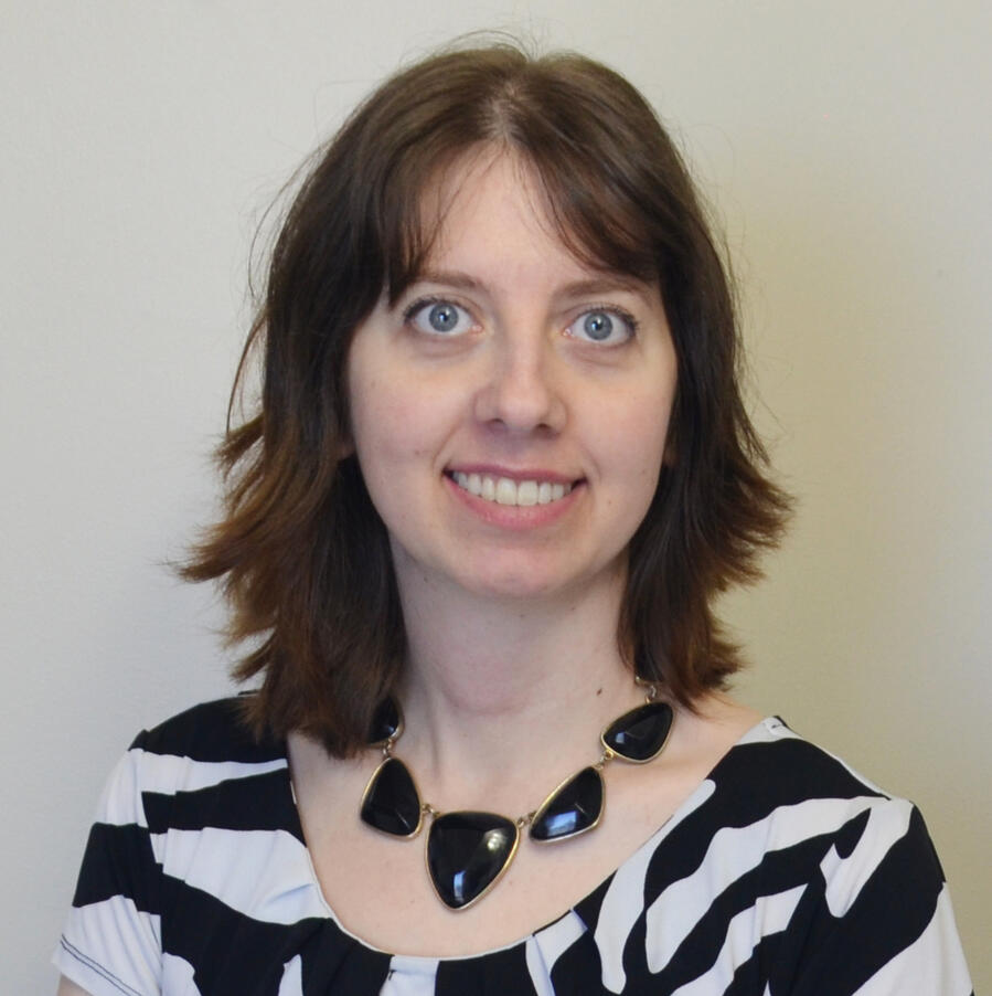 Smiling brunette, wearing a chunky geometric necklace and a zebra-print shirt.
